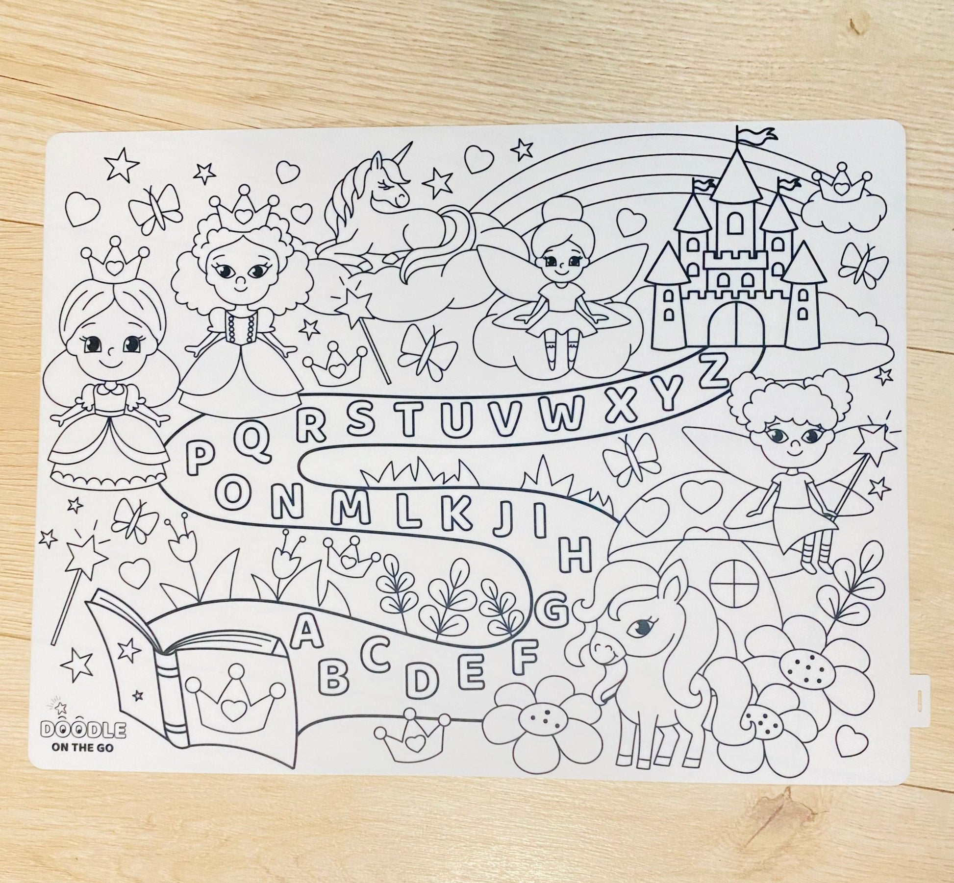Coloring page with princesses, fairies, unicorns, and castles on a wooden surface.