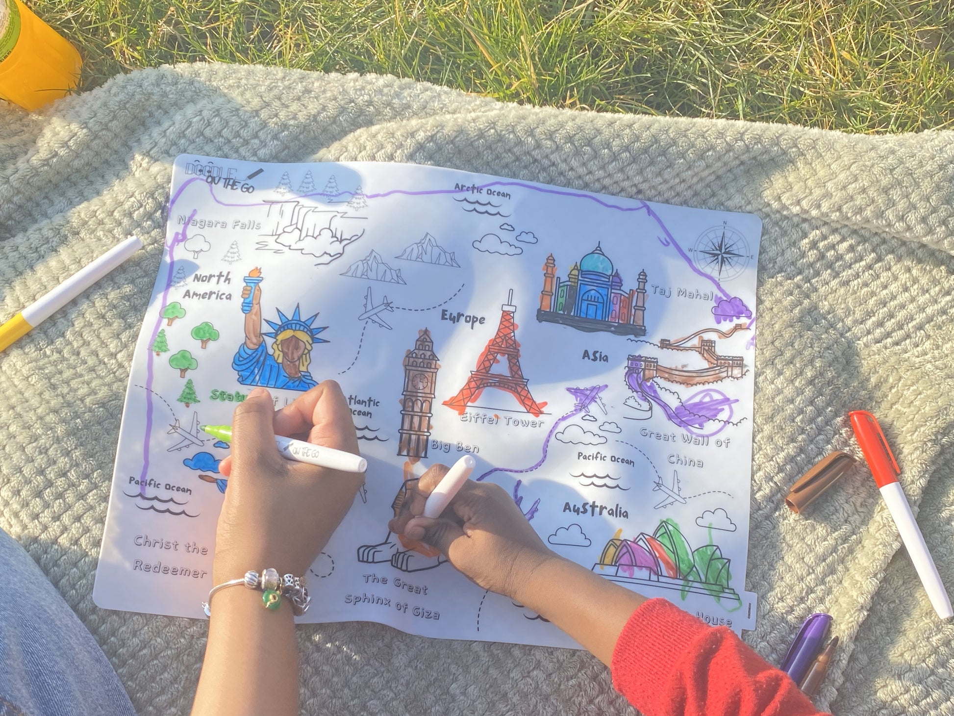 Adult and child colouring Animal Footprint Tracker mat on picnic blanket outdoors